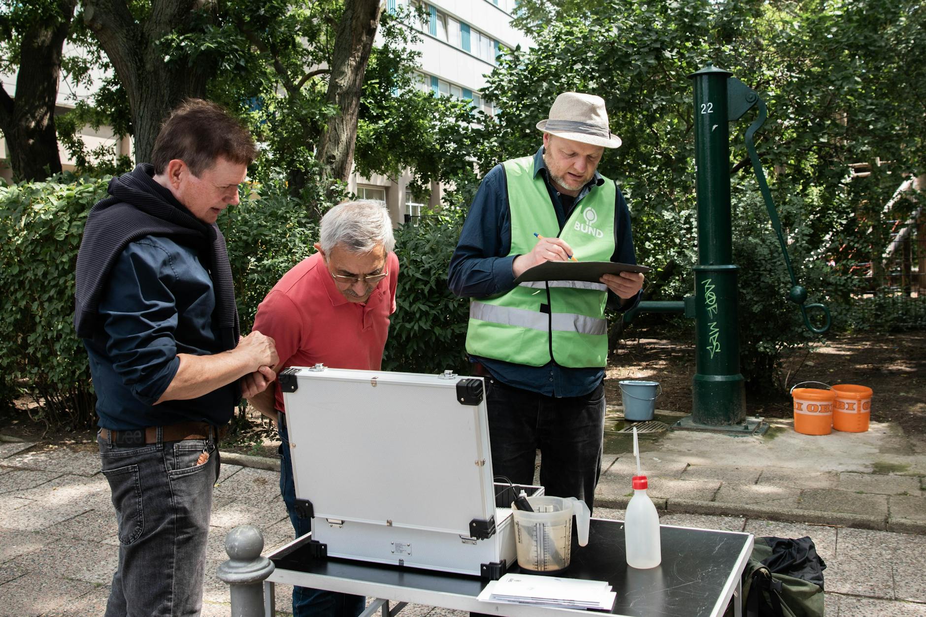 Wie warm ist das Grundwasser in 25 Metern Tiefe? Der BUND-Grundwasser-Experte Christian Schweer (r.) und die Freiwilligen Lutz Schwarzkopf (l.) und Said Modaressi mit ihren Messgeräten an der Schwengelpumpe auf der Fischerinsel.