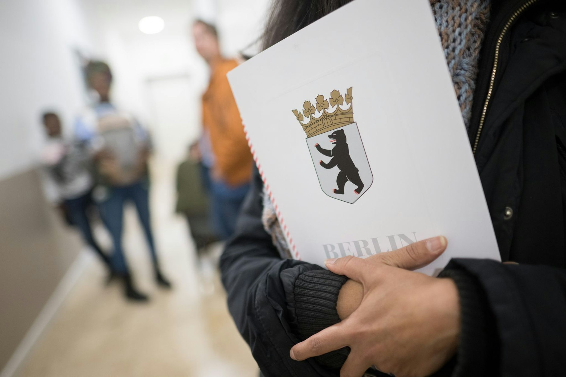 Eine Frau hält im Bürgeramt im Landesamt für Einwanderung (LEA) ihre Einbürgerungsurkunde in der Hand.