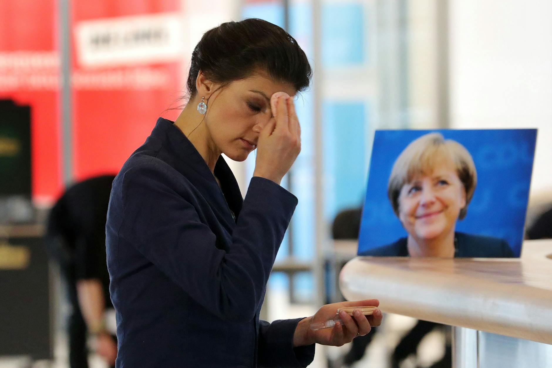 Selten vereint auf einem Foto: Sarah Wagenknecht schminkt sich 2018 vor einem Interview im Reichstagsgebäude. Auf einem Tisch steht das Portrait von Kanzlerin Angela Merkel.