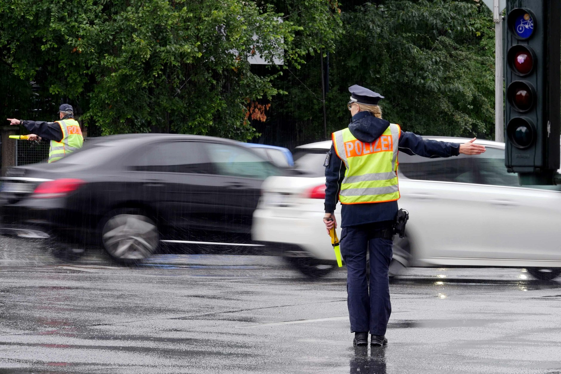 Nach dem Ausfall einer Ampel: Polizisten regeln bei strömenden Regen den Verkehr an einer Kreuzung.