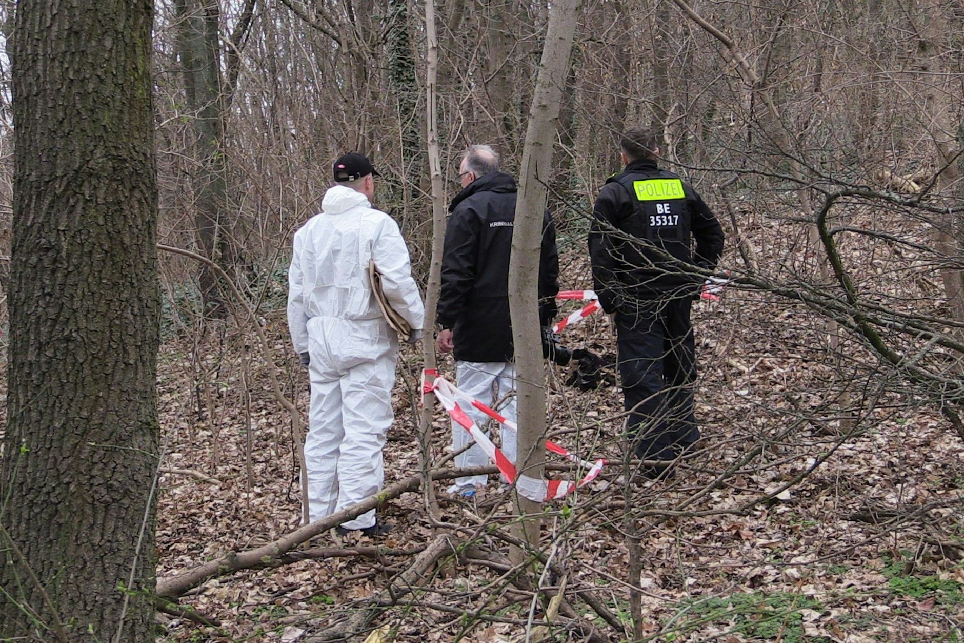 Kriminaltechniker stehen im Gestrüpp an einer Fundstelle.