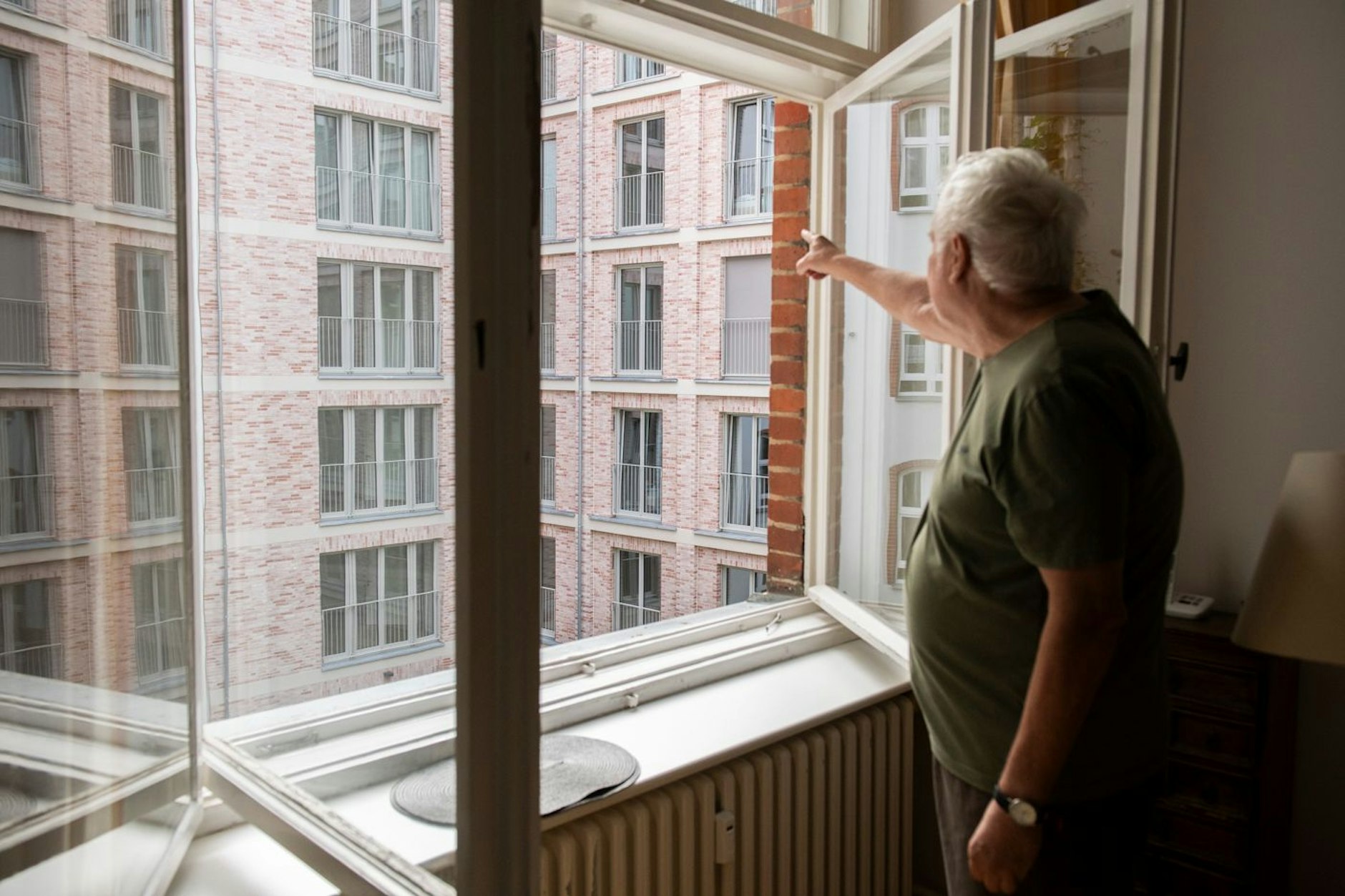 Rolf Schikorr an seinem Wohnzimmerfenster, hinten das neue Hofgartenhaus