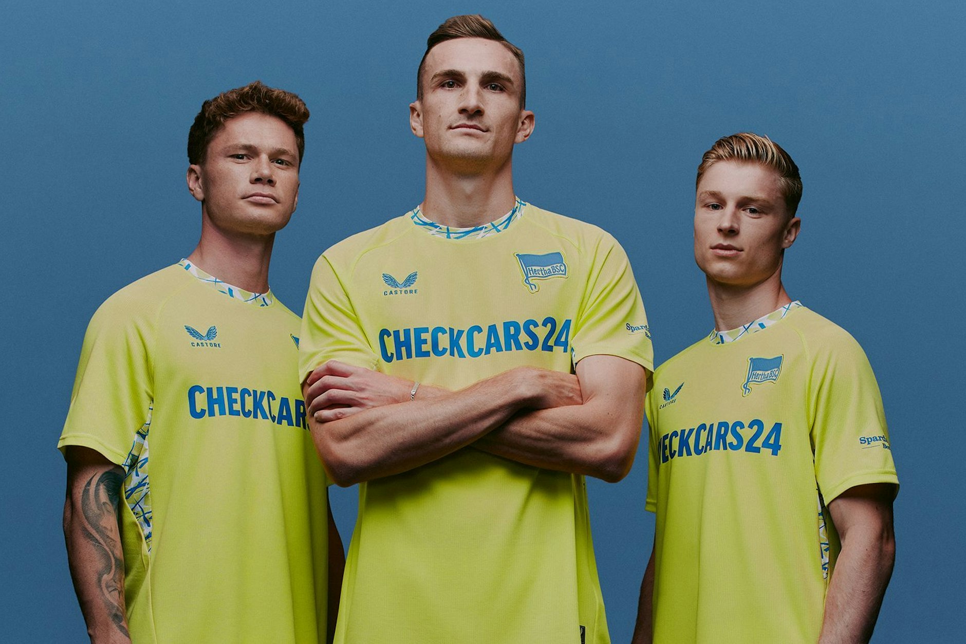 Sebastian Grönning, Niklas Kolbe und Julian Eitschberger posieren im gelben Ausweich-Trikot von Hertha BSC. 