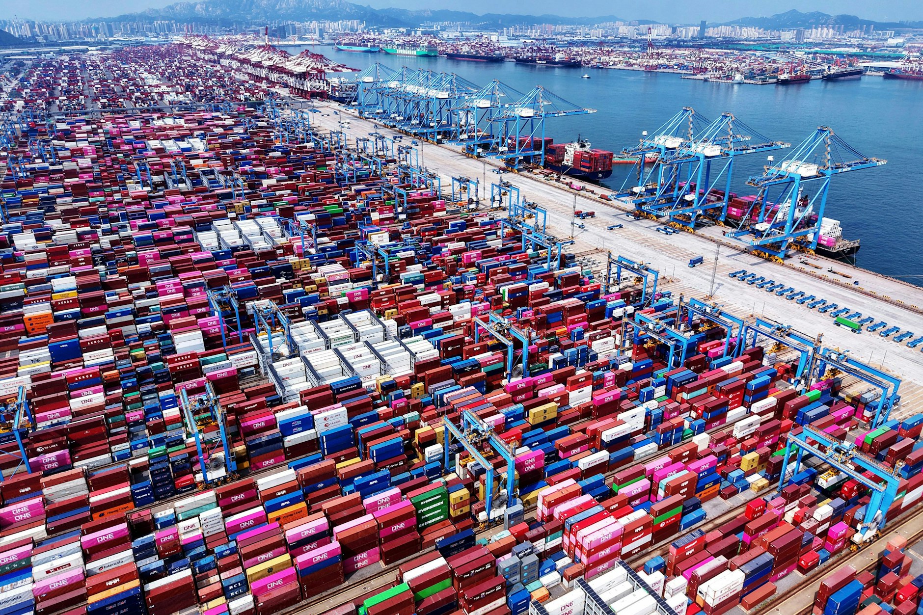 China, Qingdao: Kräne laden Container und entladen sie von Schiffen in einem Containerterminal in der ostchinesischen Provinz Shandong. 
