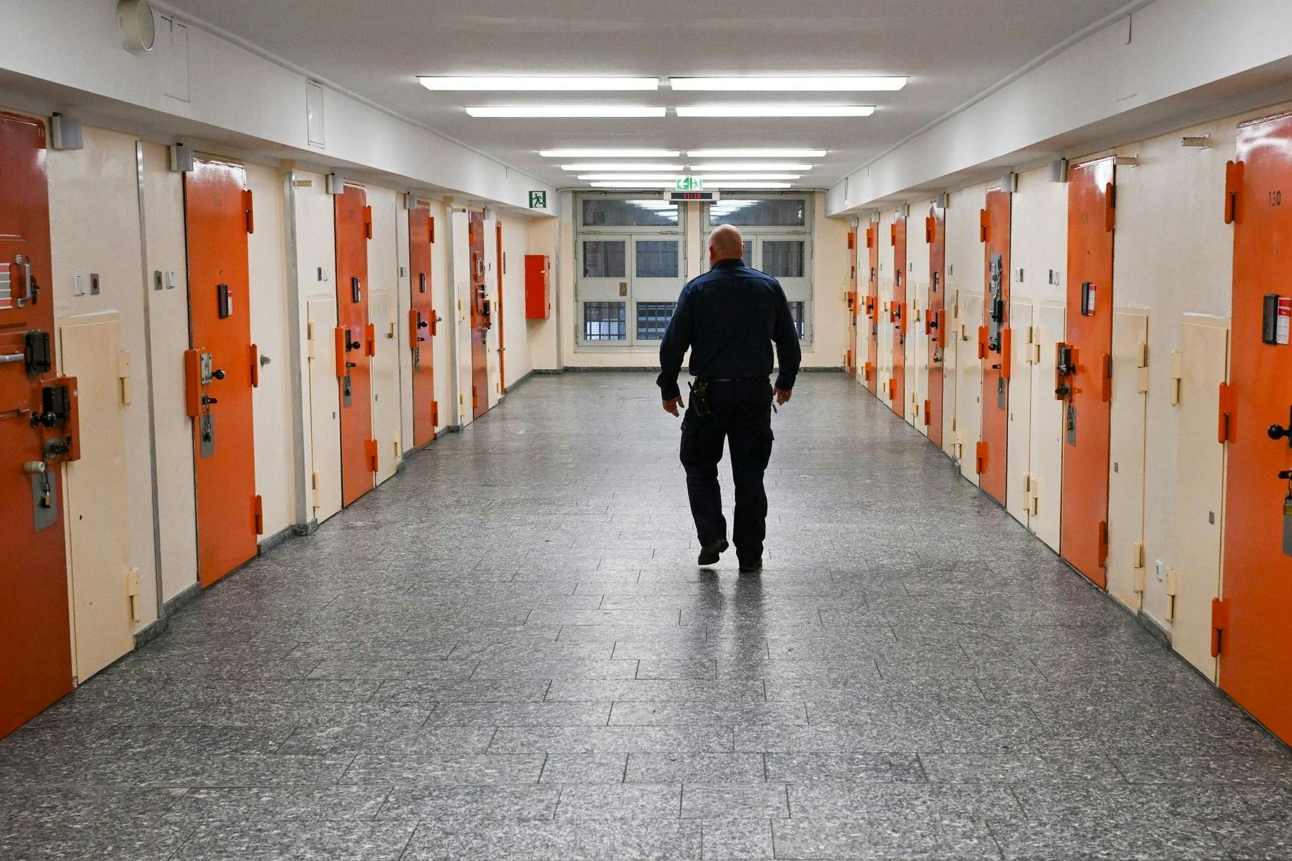 Ein Vollzugsbeamter geht in der Justizvollzugsanstalt Moabit an Zellentüren vorbei.