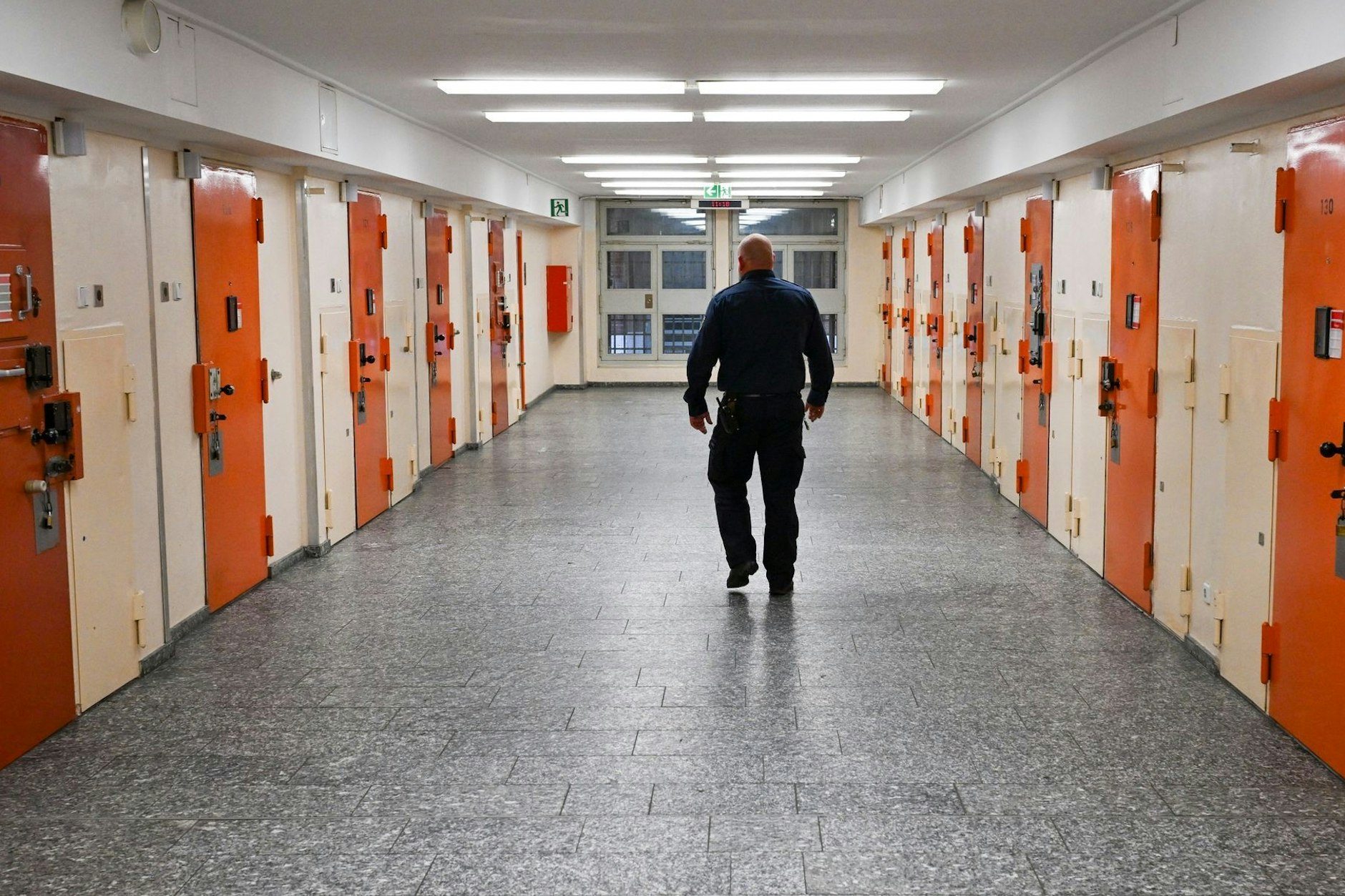 Ein Vollzugsbeamter geht in der Justizvollzugsanstalt Moabit an Zellentüren vorbei.