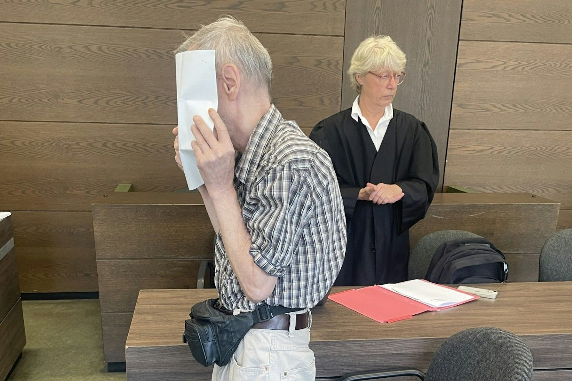 Bei der Verhandlung vor Gericht in Berlin wegen Drogenschmuggels verbirgt der angeklagte Rentner sein Gesicht hinter Papier.