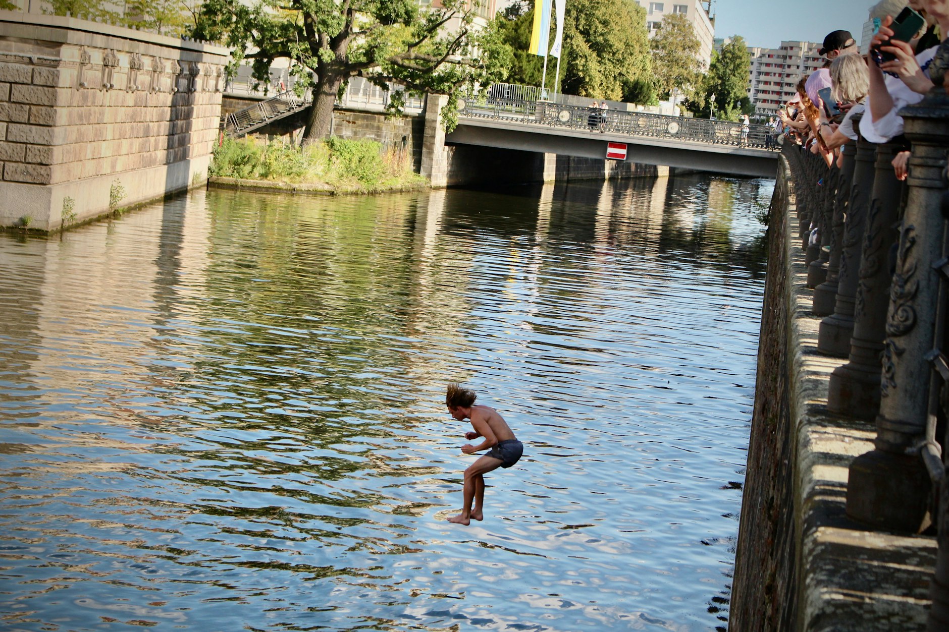 Ein Teilnehmer der Demo stößt sich vom Geländer ab, und hüpft als einer der Ersten in die Spree!