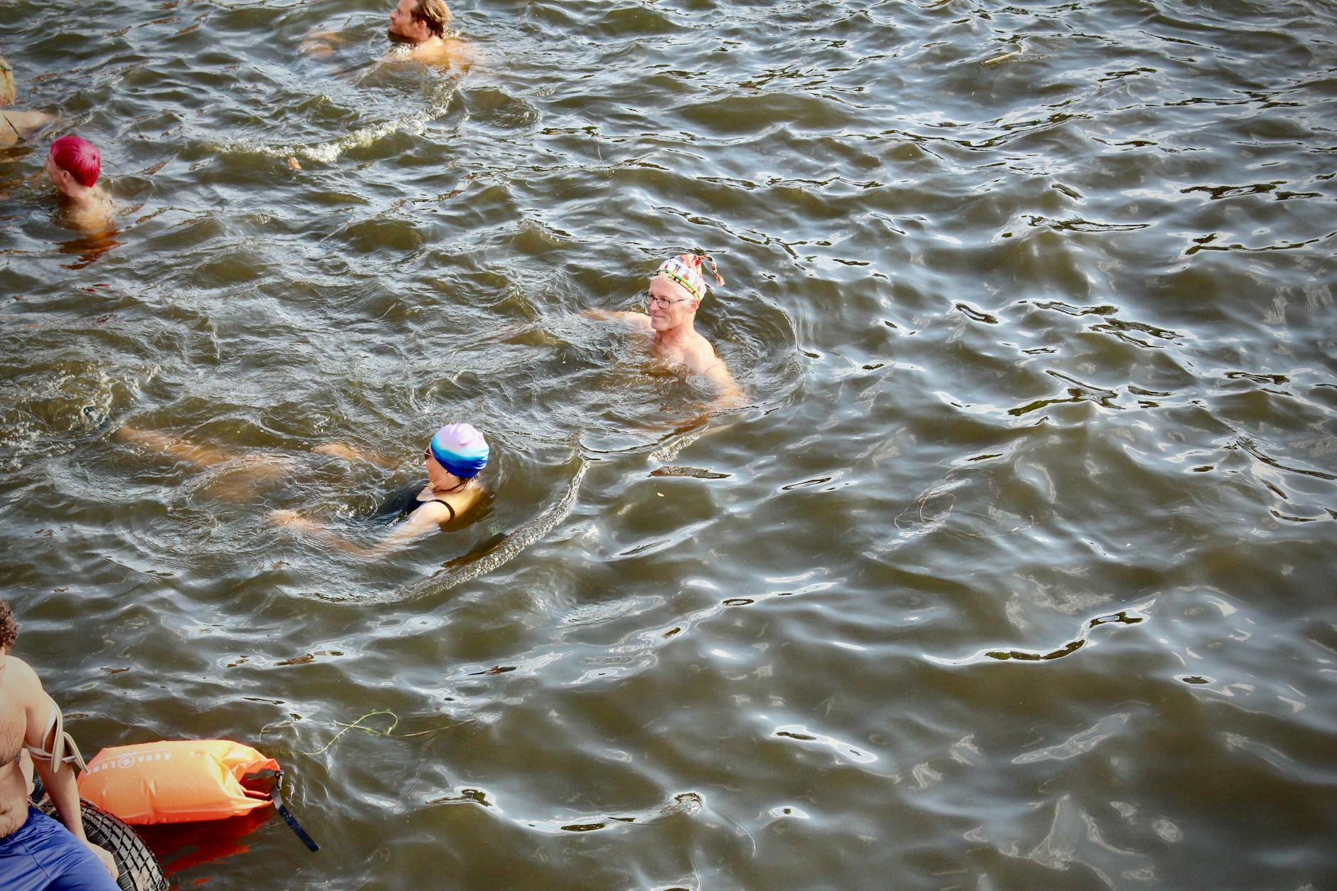 Der Geografie- und Sportlehrer Robert Neja (56) aus Steglitz-Zehlendorf (mit bunter Mütze) genießt das warme Spreewasser: „Es ist gar nicht eklig, nur ein paar Pflänzchen, das gehört dazu. Ich könnte mir gut vorstellen, hier öfter zu baden.“