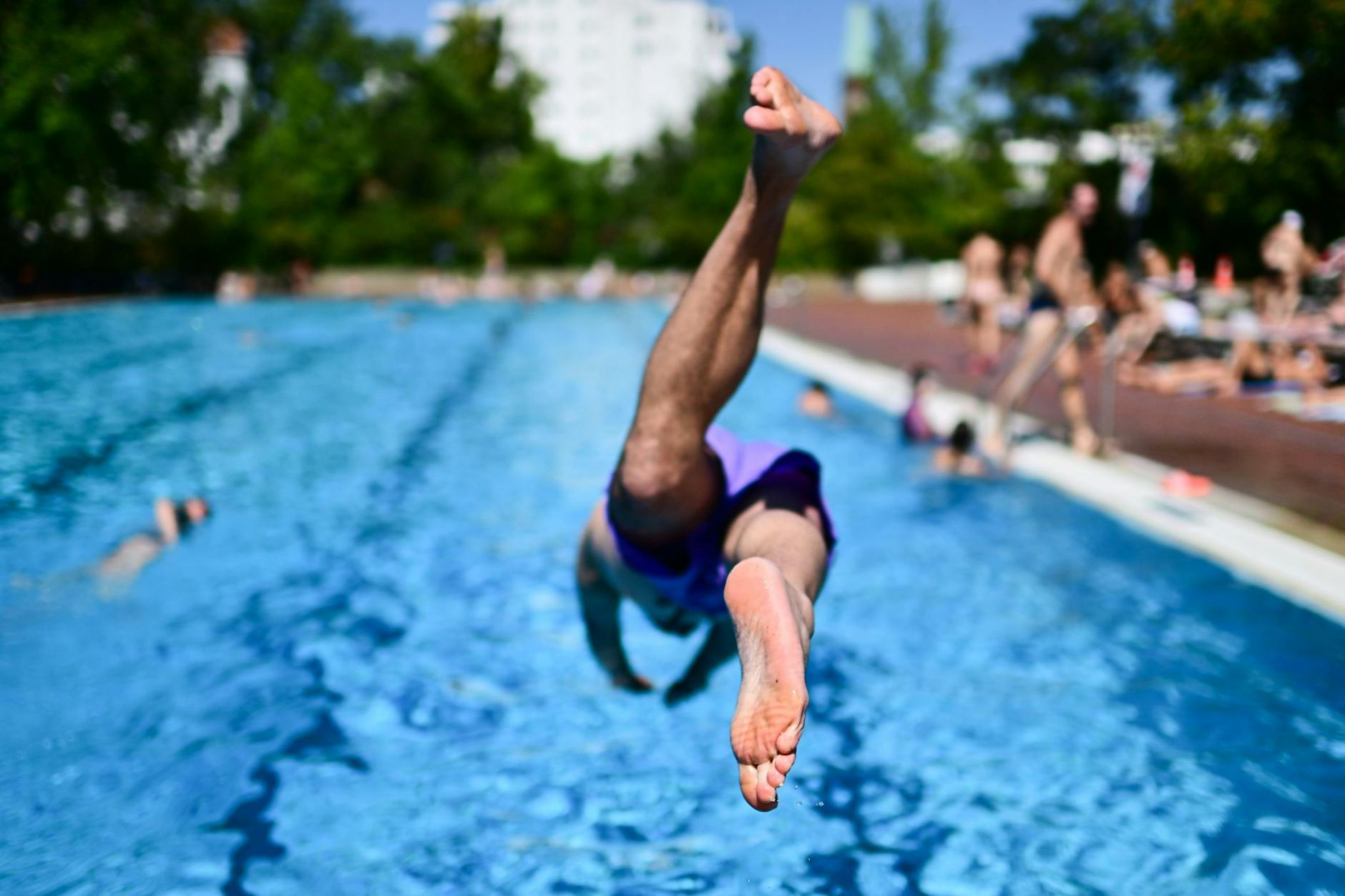 Ein Mann springt in ein Schwimmbecken. Es könnte bald zu einem Ansturm auf die Berliner Freibäder kommen.