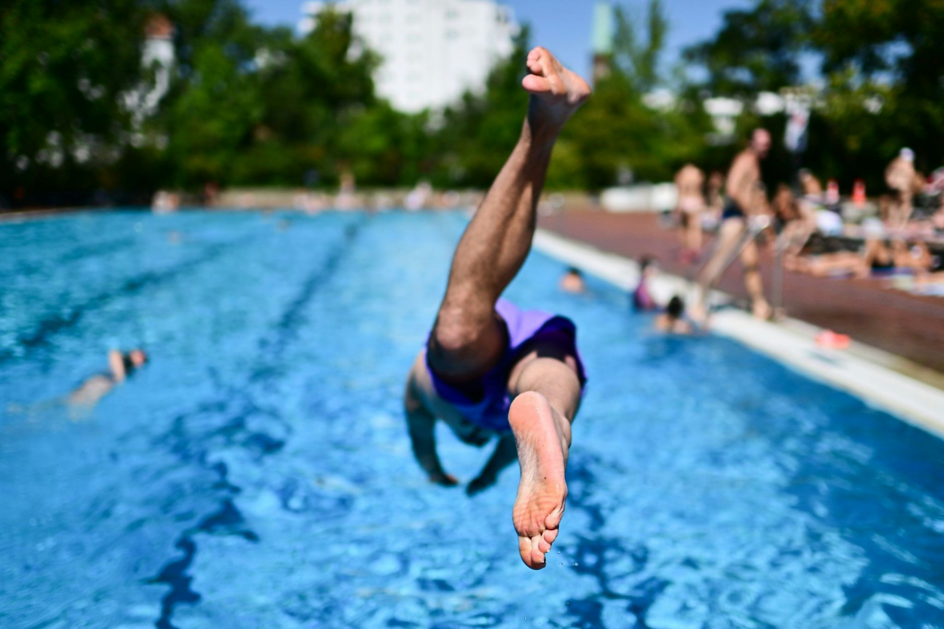 Ein Mann springt in ein Schwimmbecken. Es könnte bald zu einem Ansturm auf die Berliner Freibäder kommen.