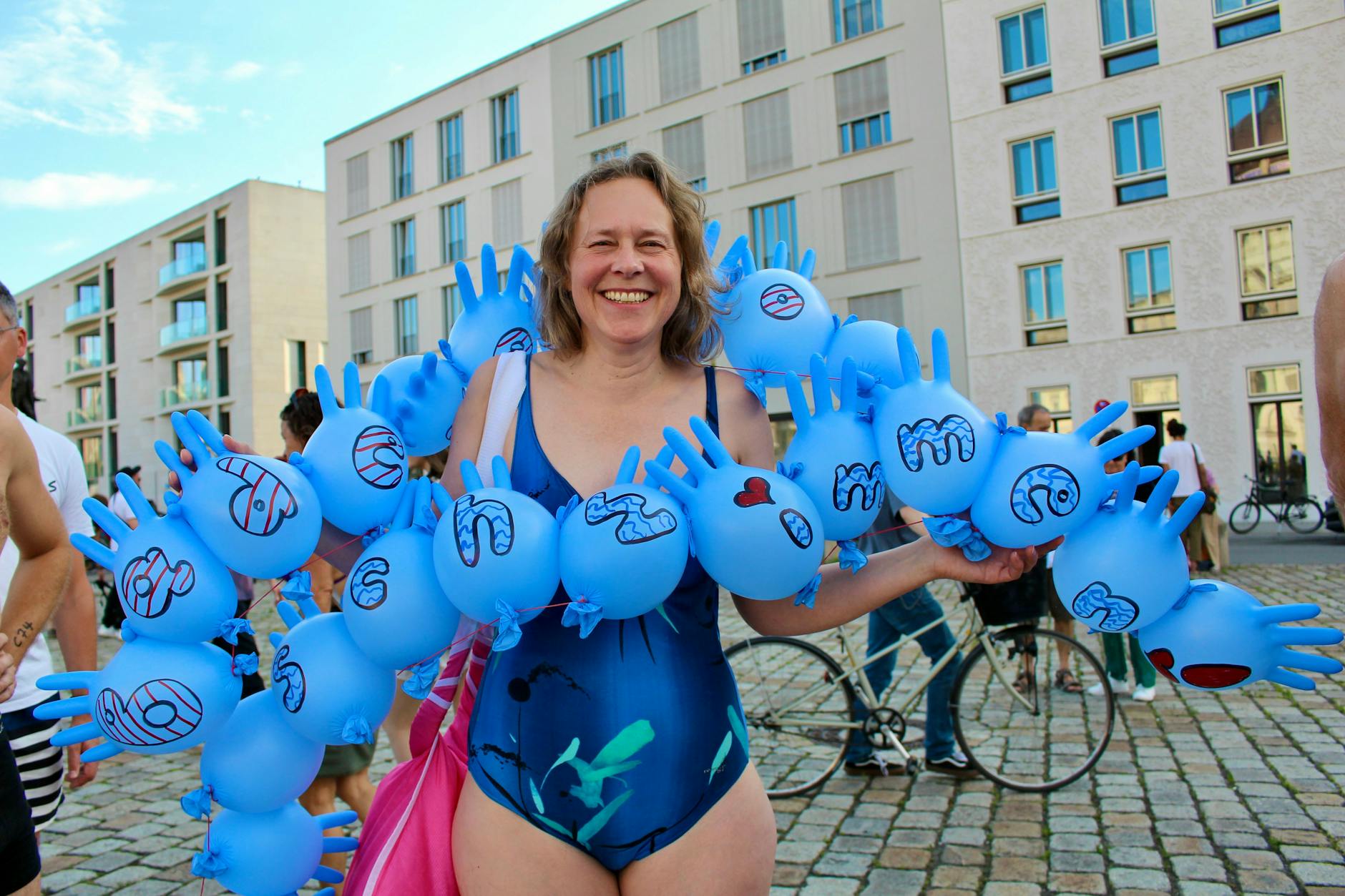Eva-Maria Lutz (59) aus Steglitz gekleidet in aufgeblasenen Einmalhandschuhe mit der Aufschrift „Badeverbot wegschwimmen!“. Seit zehn Jahren bei Fluss Bad Berlin schwimmt sie für das Nutzen innerstädtische Gewässer.