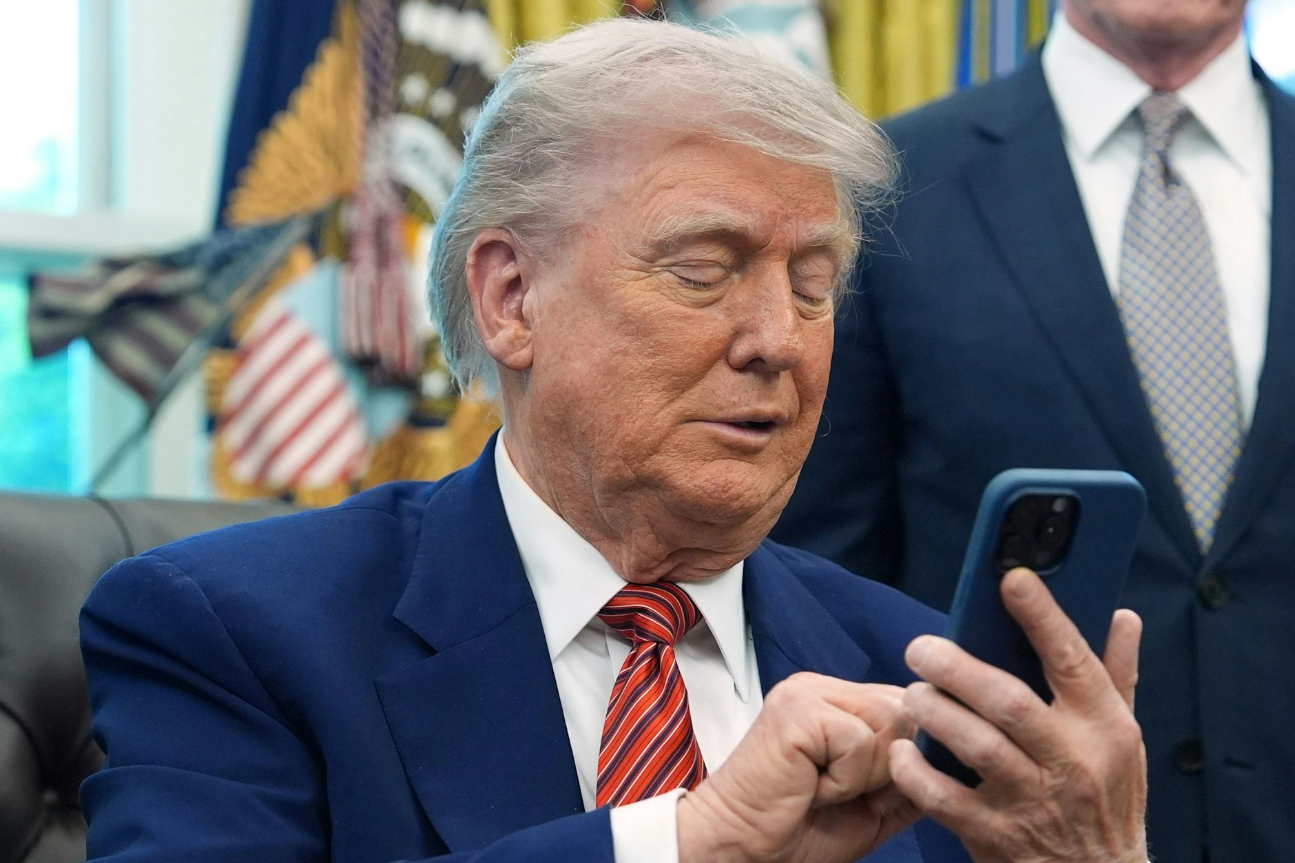US-Präsident Donald Trump blickt auf sein Handy.