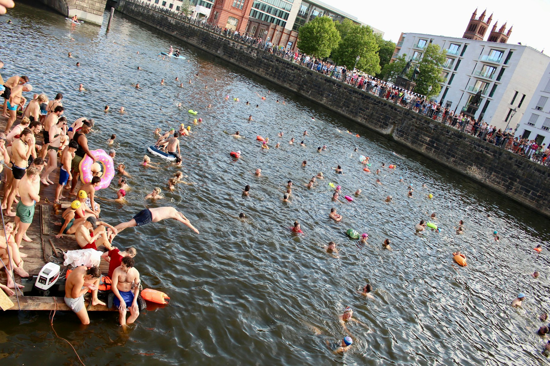 Mit Gelächter und Spritzwasser springen die Teilnehmer der Mitschwimm-Demo vom Steg ins warme Spreewasser.