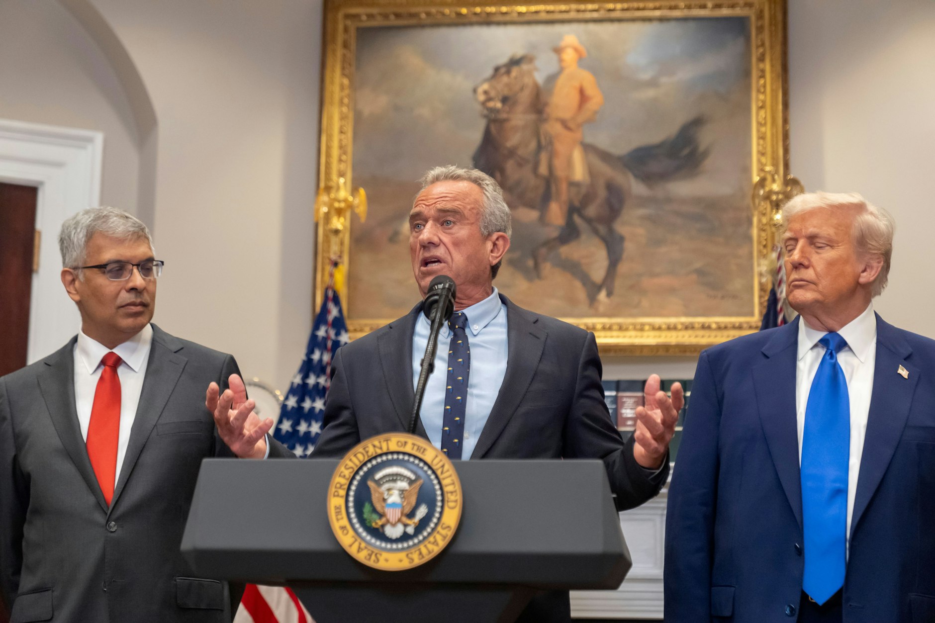 US-Gesundheitsminister Robert F. Kennedy Jr. (M.) spricht in Washington, daneben Jay Bhattacharya (l.), Direktor der National Institutes of Health, und US-Präsident Donald Trump (r.).