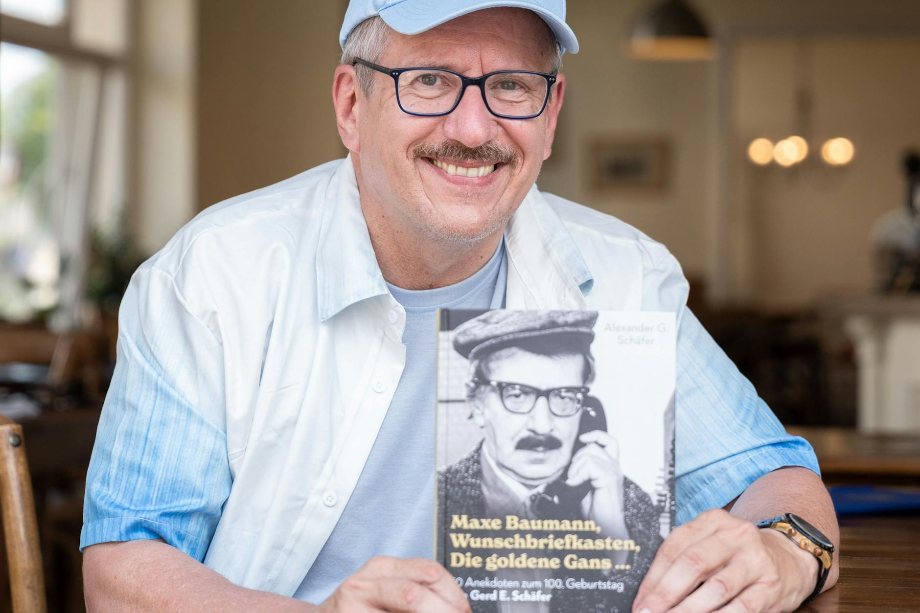 Die Ähnlichkeit ist verblüffend: Alexander G. Schäfer mit seinem Buch über seinen Vater Gerd E. Schäfer, der vor fast 50 Jahren das erste Mal die Rolle von Maxe Baumann spielte.