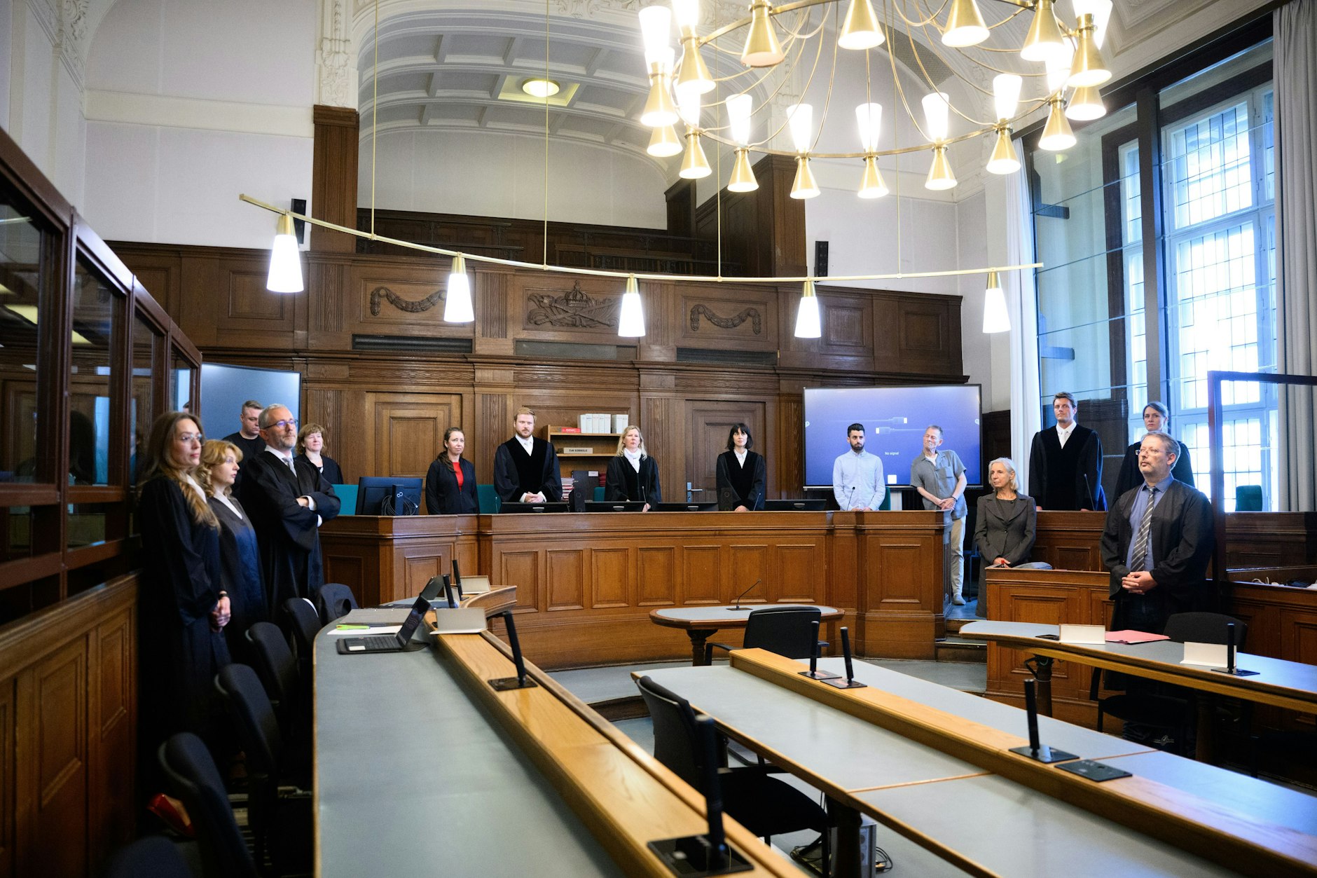 Beim Prozessbeginn stehen die Rechtsanwälte des Angeklagten, Klaudia Dawidowic, Ria Halbritter und Christoph Stoll (v. l.) sowie die Vorsitzende Richterin Sylvia Busch (M) und Staatsanwalt Philipp Meyhöfer (2.v.r.) im Landgericht Berlin.