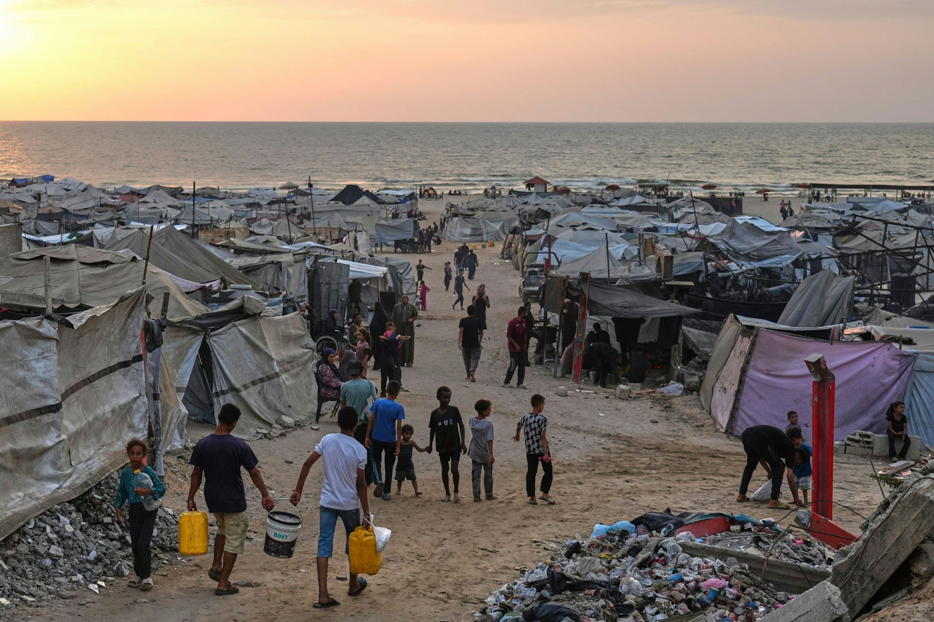 Vertriebene Palästinenser gehen durch ein behelfsmäßiges Lager am Strand von Gaza-Stadt.