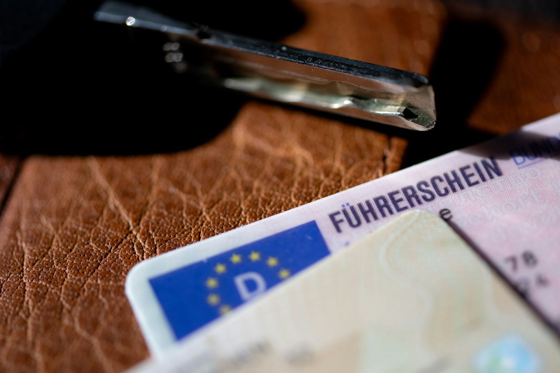Ein Führerschein, ein Autoschlüssel und ein Personalausweis liegen auf einem Portemonnaie.