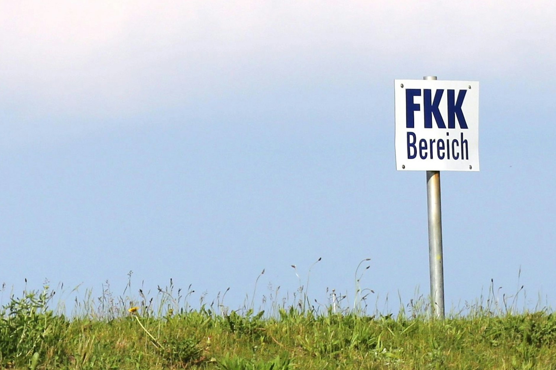 Ein Schild weist auf den FKK-Bereich an einem Strand hin.