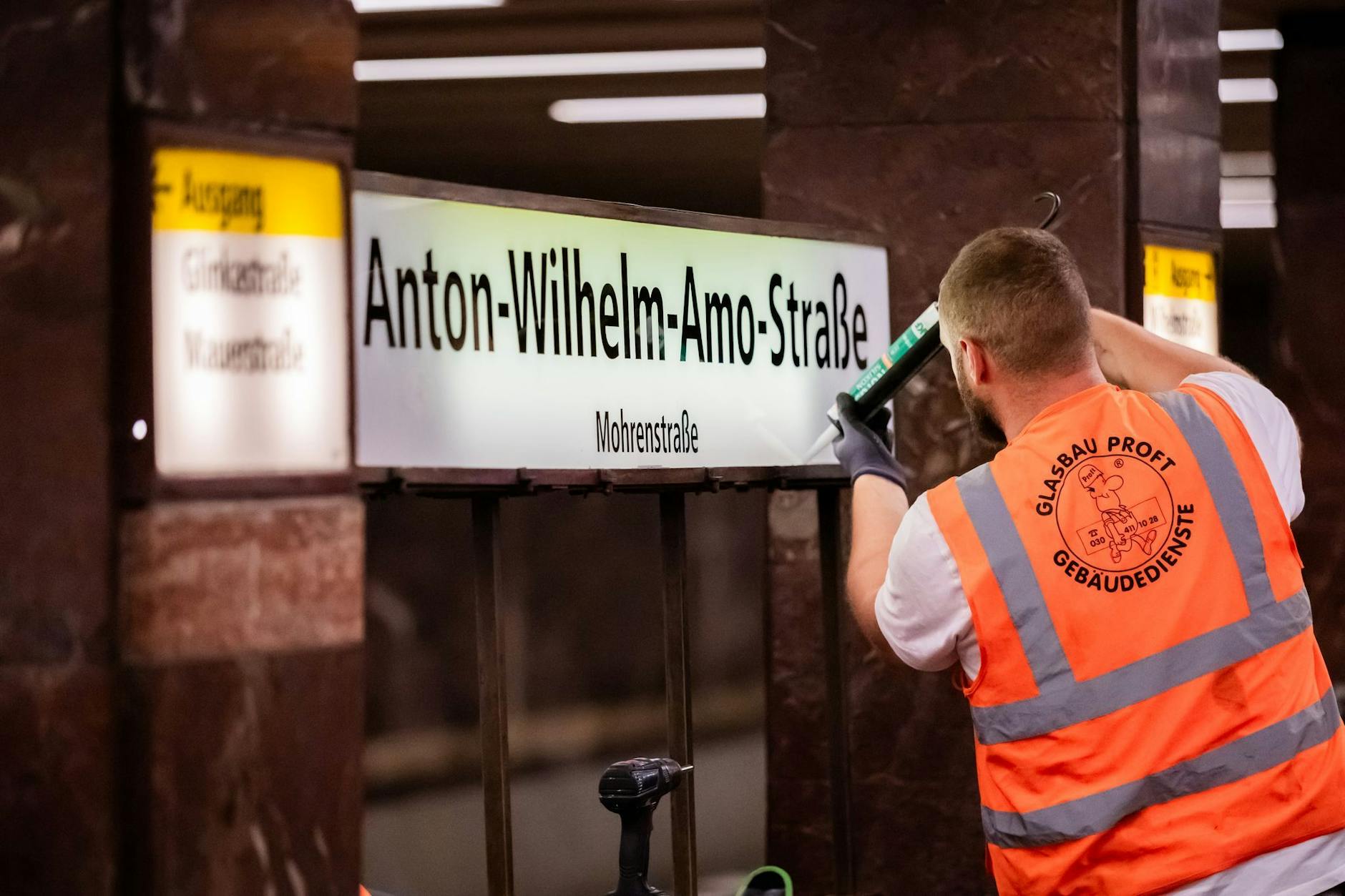 Ein Glasbauer montiert während der Betriebspause die neuen Schilder mit der Aufschrift „Anton-Wilhelm-Amo-Straße“ im bisherigen U-Bahnhof Mohrenstraße.