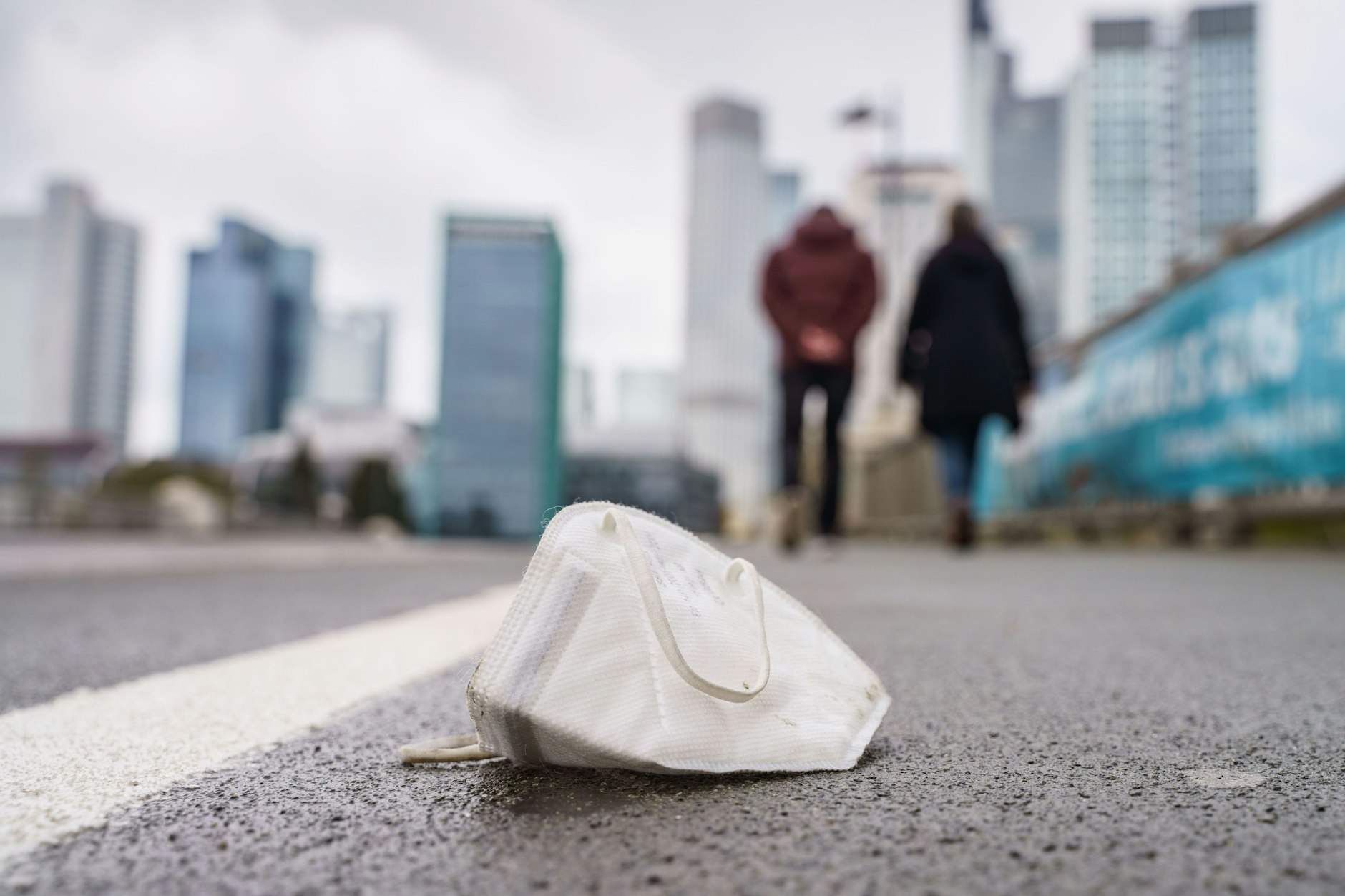 Eine Corona-Maske liegt auf einem nassen Gehweg in Frankfurt am Main (Symbolbild).