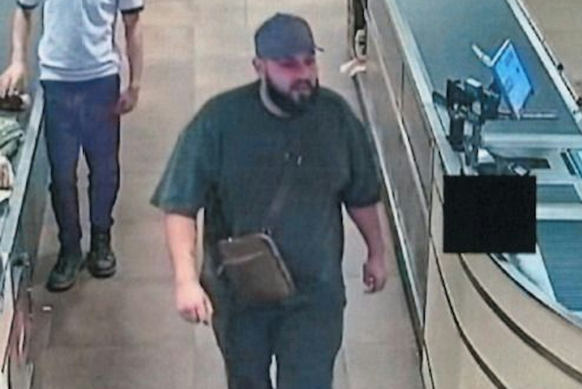 Der Mann mit Basecap lenkte während des Diebstahls die Kassiererin ab.