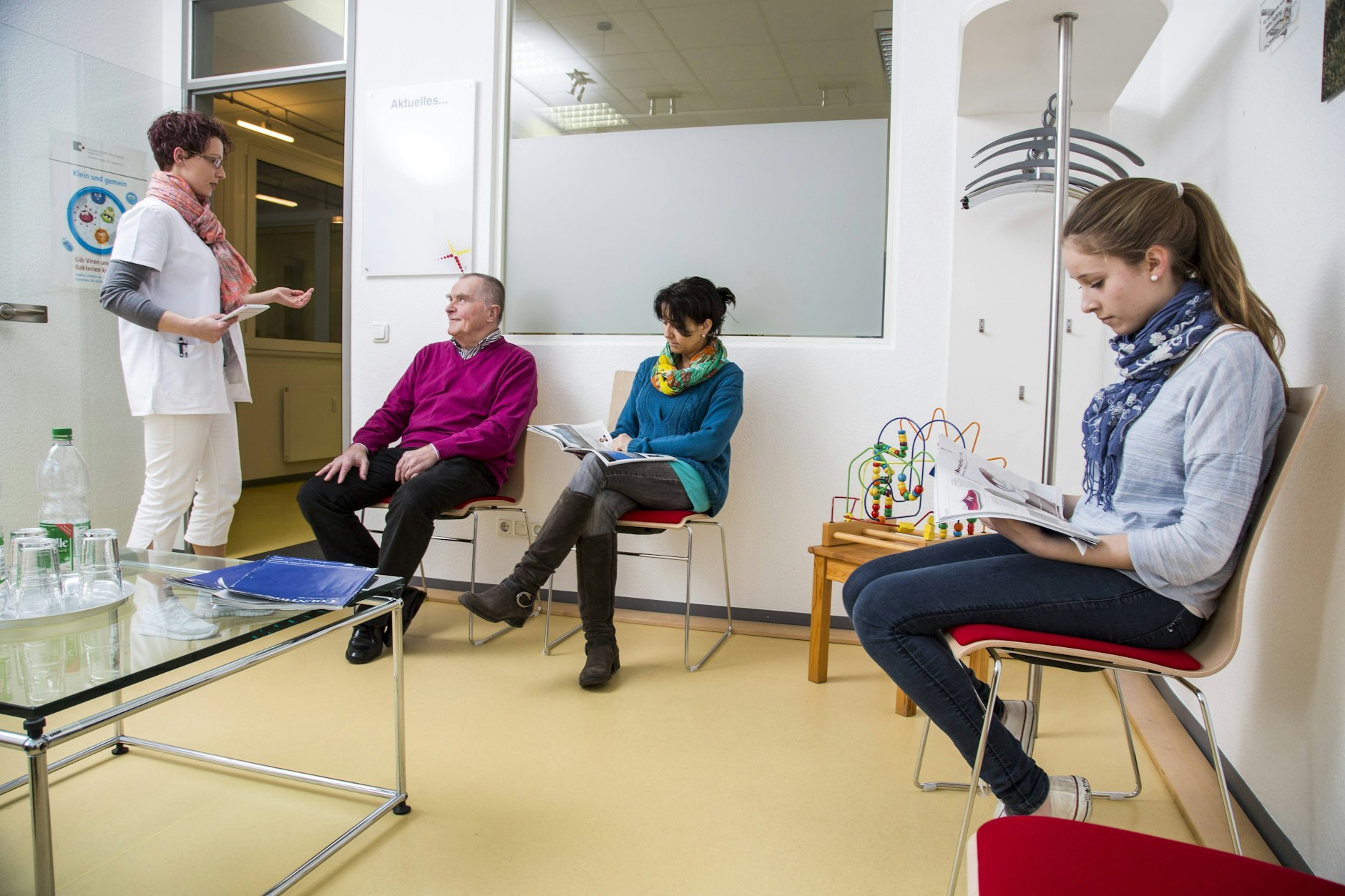 Eine Sprechstundenhilfe mit Patienten in einem Wartezimmer