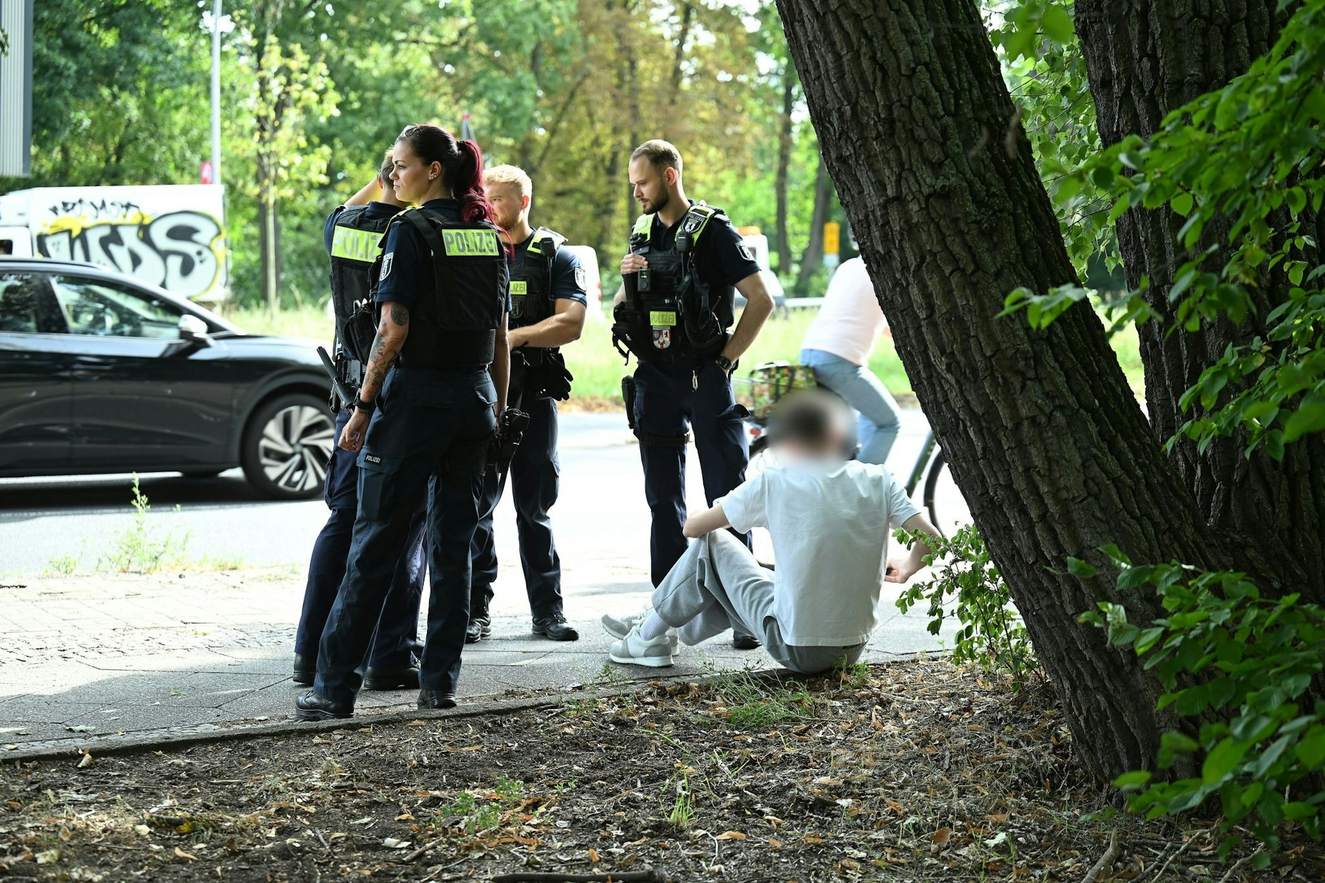 Polizisten stehen an der Unfallstelle an der Seestraße in Wedding. Der Unfallverursacher sitzt auf dem Gehsteig. Gegen ihn wird nun ermittelt.