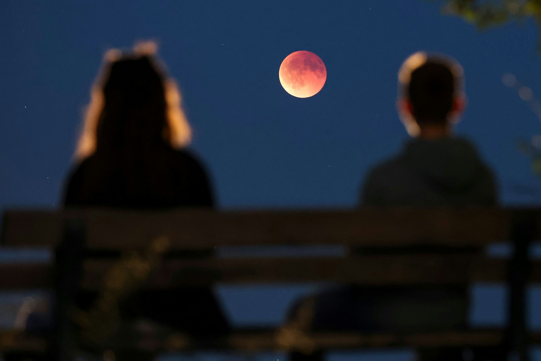 Romantik pur: Ein Pärchen betrachtet in Leipzig die Mondfinsternis, der Mond am Himmel hat sich bereits rot gefährt.