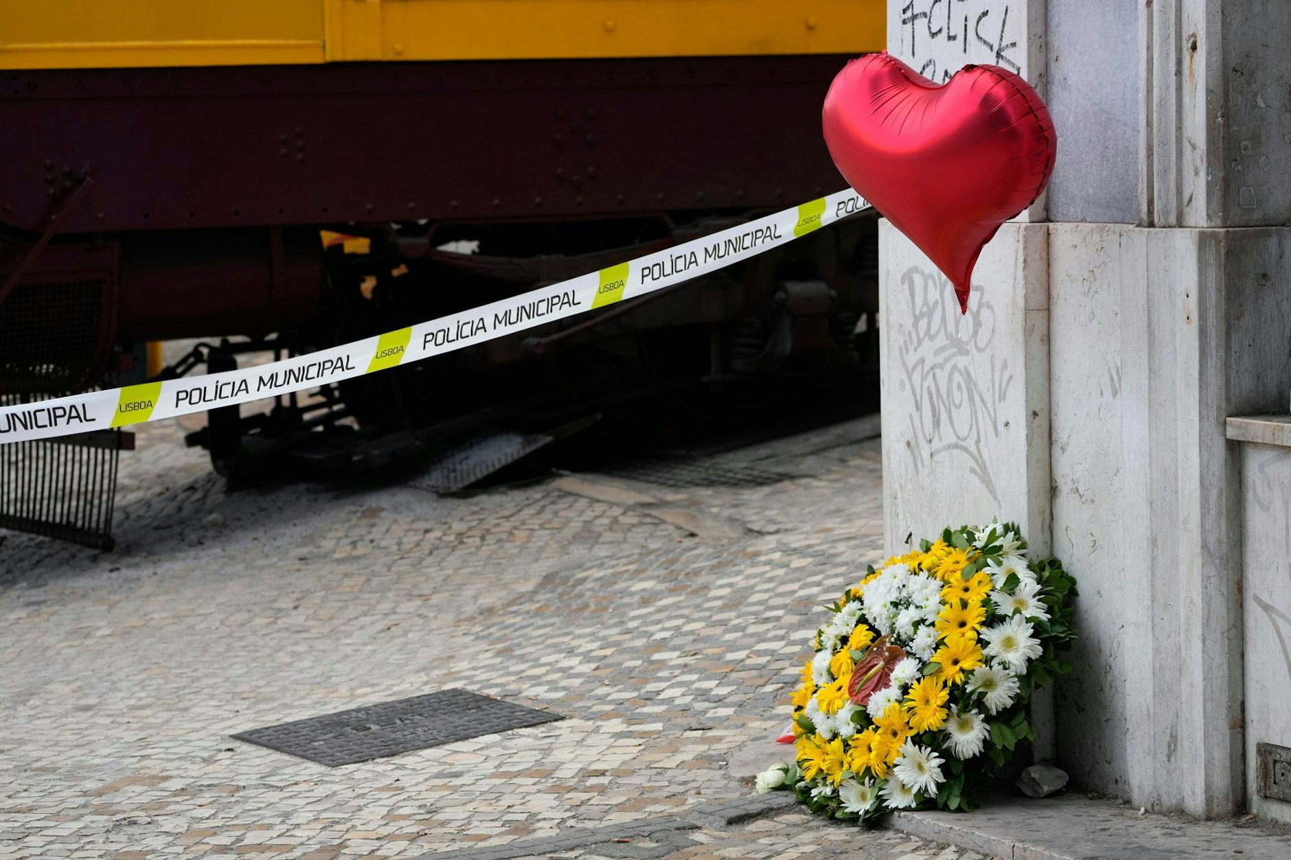 Ein Blumenkranz und ein Luftballon sind nahe der Stelle zu sehen, an der die Standseilbahn „Elevador da Gloria“ entgleiste und 16 Menschen starben.