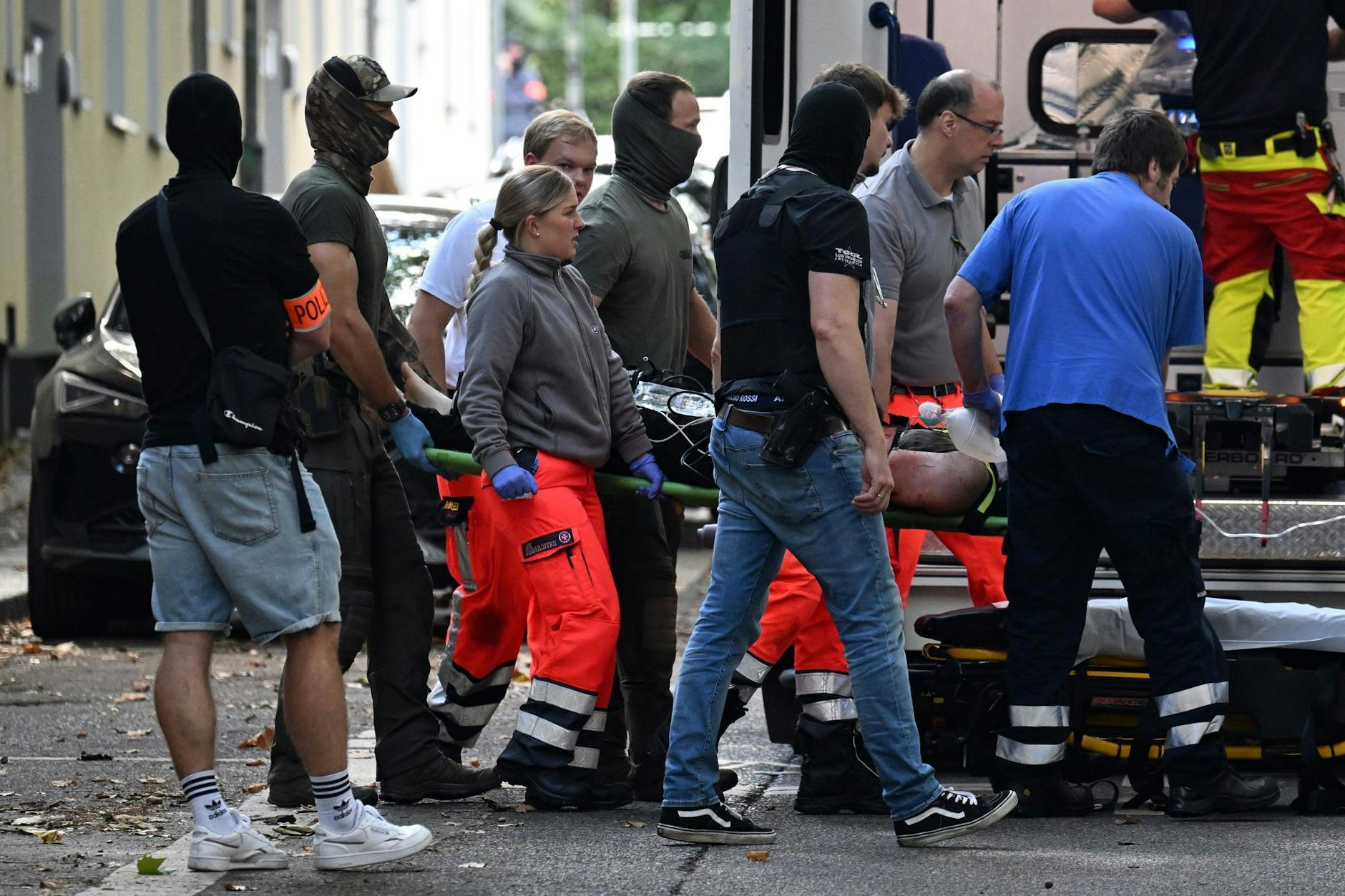 Einsatzkräfte bringen die Trage mit einem verletzten, tatverdächtigen 17-Jährigen zu einem Rettungswagen.