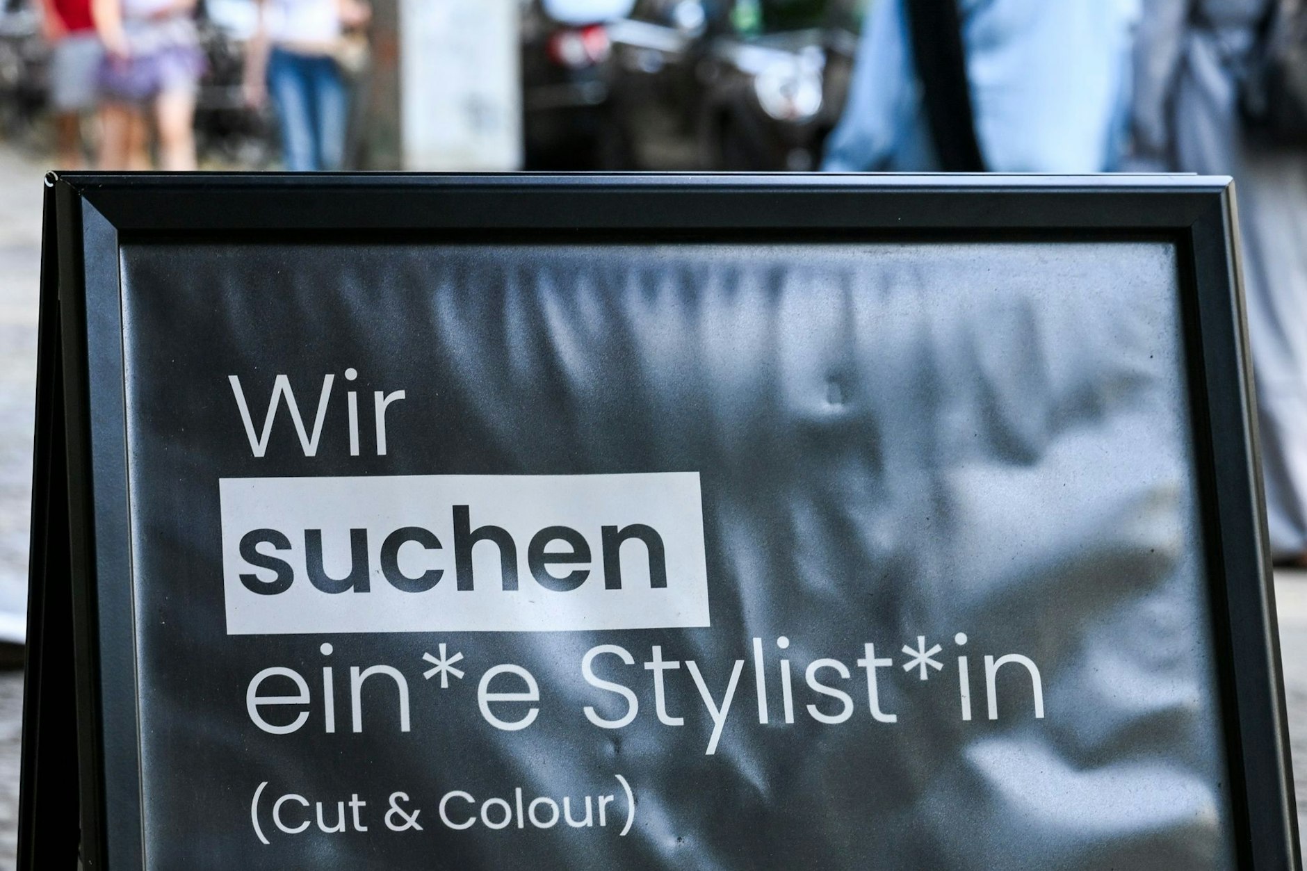 Auf einem Schild wird gendergerecht eine Stylistin beziehungsweise ein Stylist gesucht.