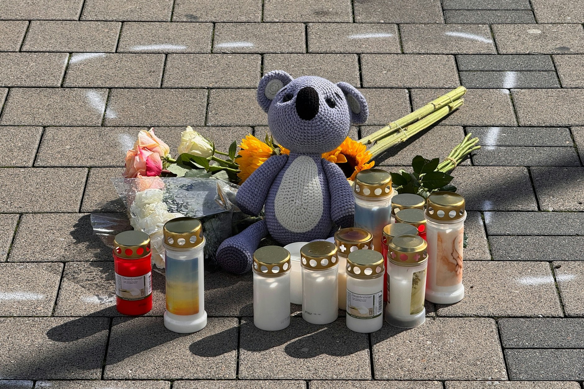 Ein Teddy, Blumen und Kerzen stehen an der Stelle, wo der 12-Jährige starb. Der Tatort ist mit Sprühfarbe markiert.