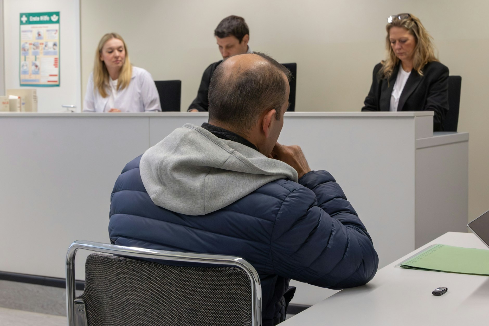 Der Angeklagte Maznun Azak sitzt in einer blauen Jacke vor dem Richter.
